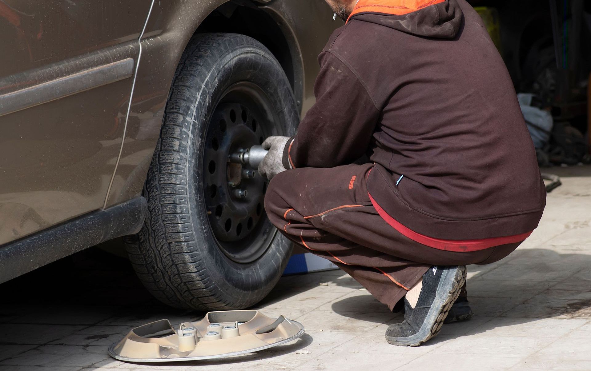 A mechanic working on a car tire, changing it in an auto repair shop.